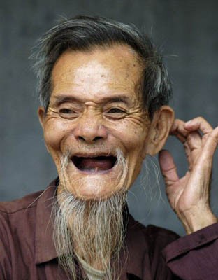 Ông lão cười tươi với nụ cười rạng rỡ, hàm răng cái còn cái rụng, thể hiện sự lạc quan và yêu đời.