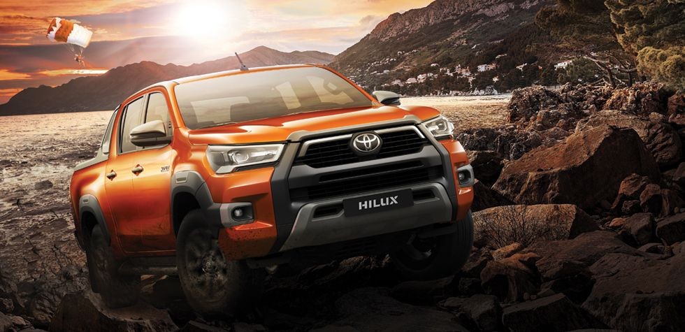 Đầu xe Toyota Hilux 2024 màu cam mạnh mẽ với lưới tản nhiệt hình thang và đèn LED sắc sảo