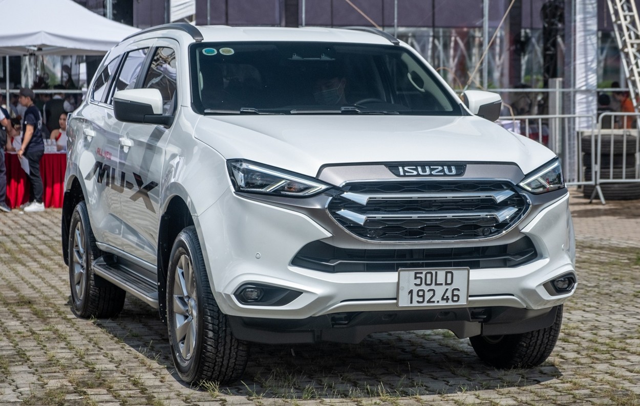 alt text: Hình ảnh xe Isuzu Mu-X màu trắng bạc đang đỗ trên bãi cỏ, nổi bật với thiết kế sang trọng
