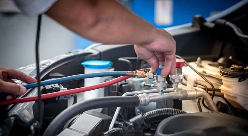 Kỹ thuật viên đang kiểm tra hệ thống điều hòa ô tô bằng thiết bị chuyên dụng.