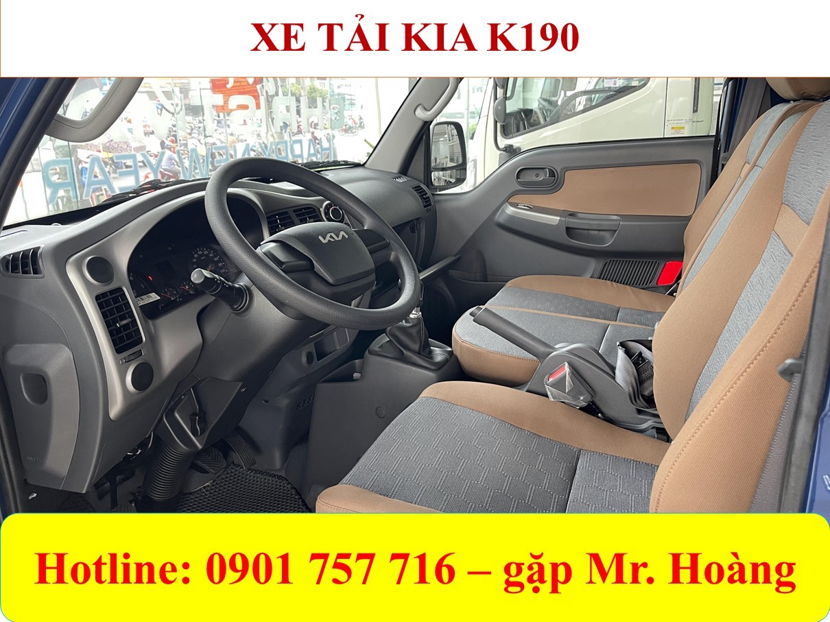 Image de l'intérieur du camion Kia K190, sièges en tissu, volant à 3 branches, tableau de bord central moderne.