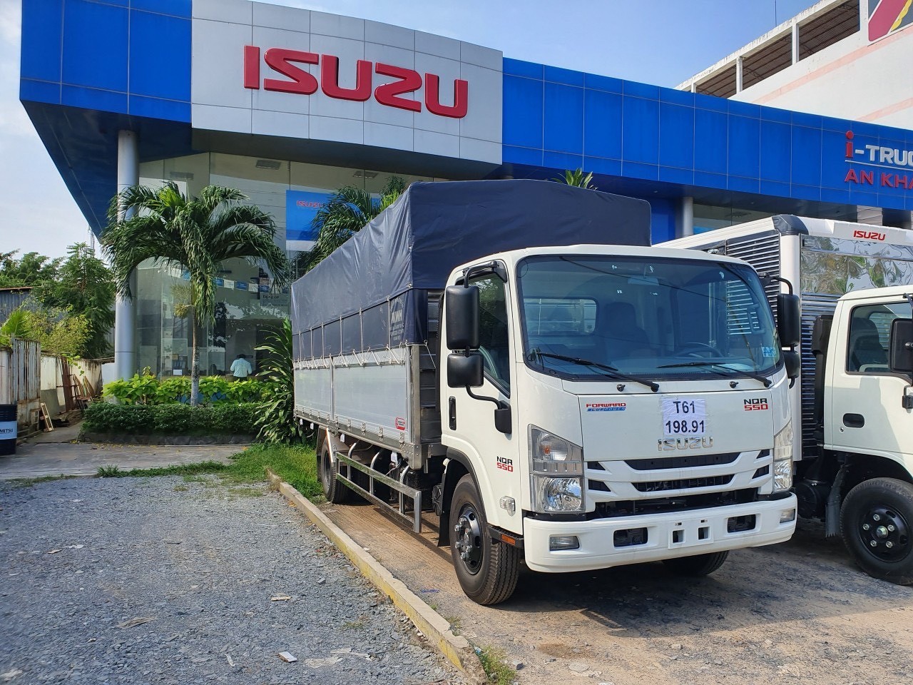 Mặt trước xe tải Isuzu NQR 550 thùng mui bạt mạnh mẽ, logo Isuzu nổi bật trên nền lưới tản nhiệt