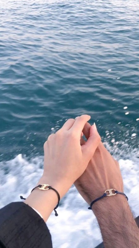 Đôi bàn tay nắm chặt nhau trên bãi cát trắng mịn, thể hiện sự gắn kết và yêu thương.