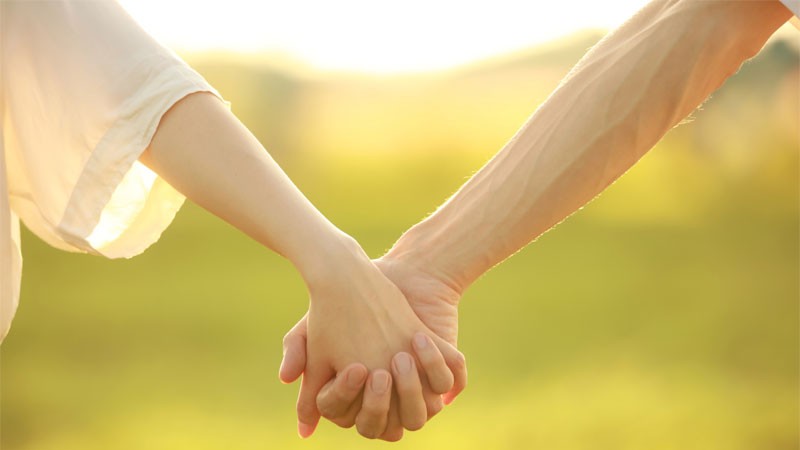 Cặp đôi nắm tay nhau khi nấu ăn cùng nhau, thể hiện sự chia sẻ và quan tâm.