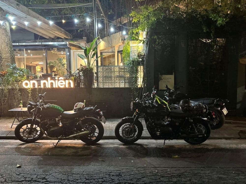 Không gian bên ngoài quán cafe An Nhiên Khúc Hạo với cây xanh và ánh sáng ấm áp