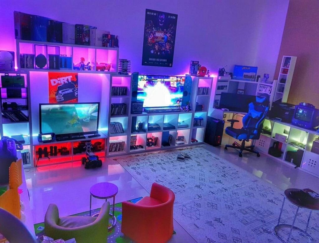 Một phòng chơi game sáng sủa và đầy màu sắc với TV lớn, PC chơi game và ghế thoải mái.