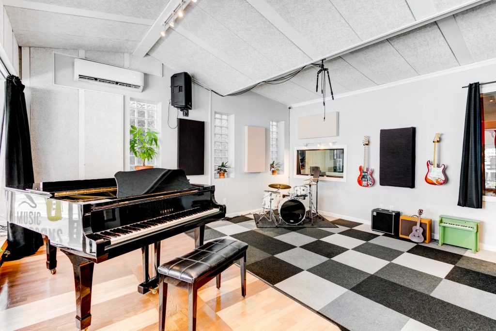 Phòng nhạc với đàn piano lớn, trống, guitar và các nhạc cụ khác.