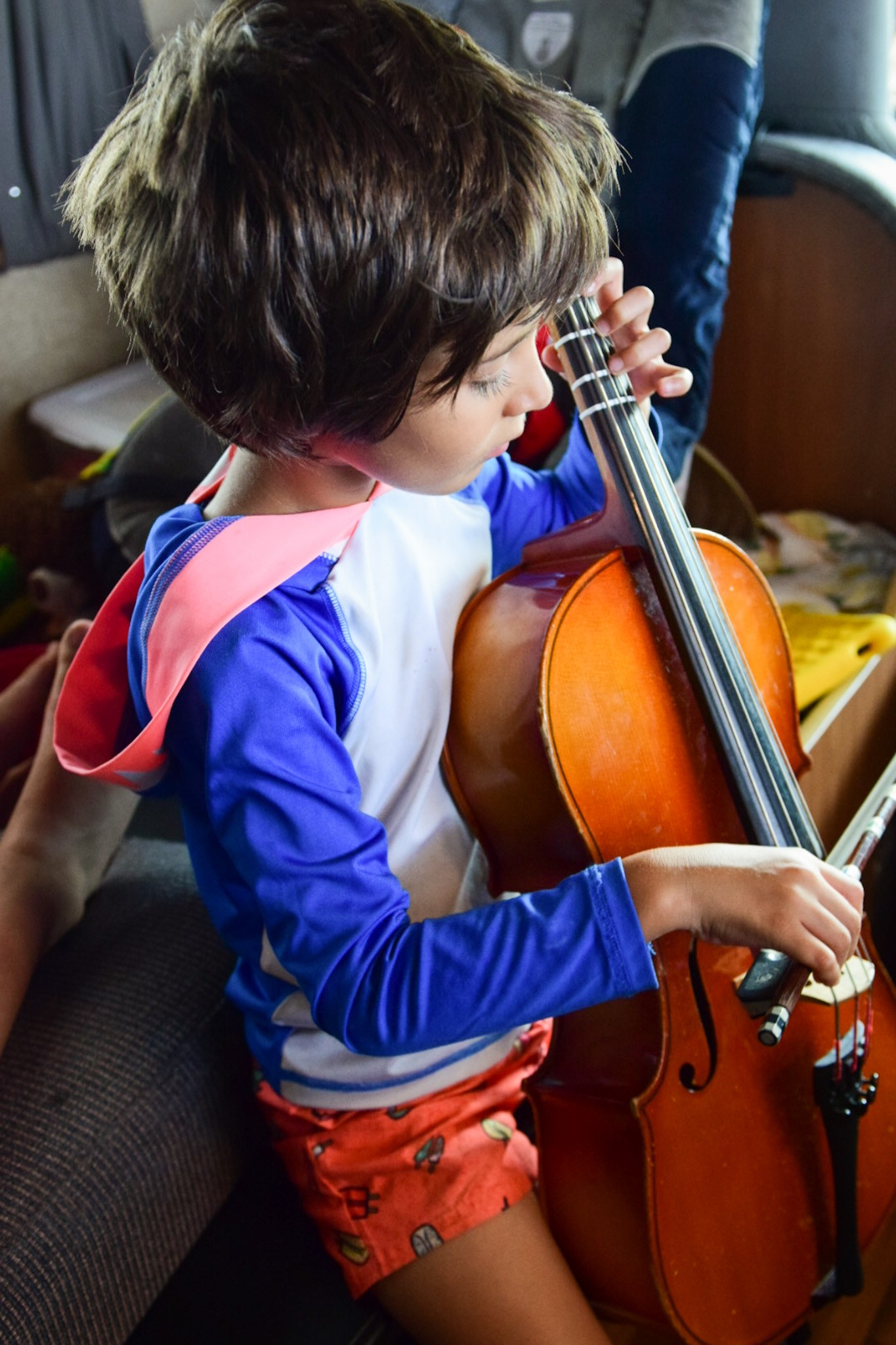 Hình ảnh minh họa cho thấy một bé trai đang chơi đàn violin với sự thích thú