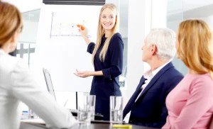 Người đàn ông mặc áo vest đang chỉ tay lên màn hình lớn trong phòng họp, thể hiện sự tự tin và quyết đoán.