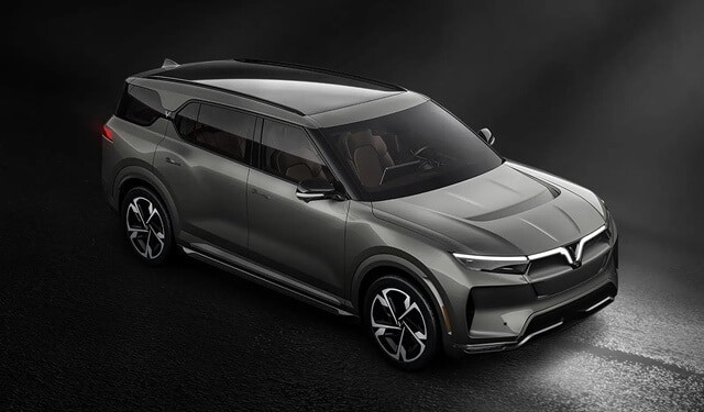 Hình ảnh xe VinFast VF 9 màu xanh đậm mạnh mẽ đậu trước một biệt thự sang trọng