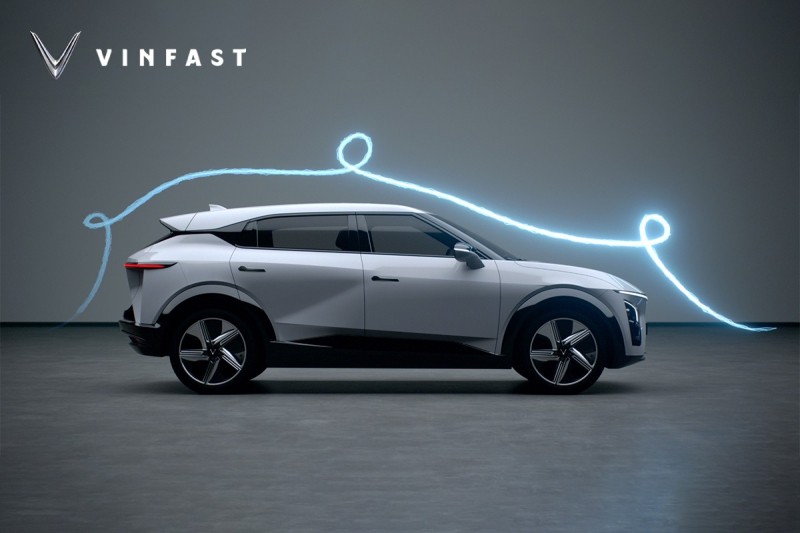 Hình ảnh xe VinFast VF 7 màu đỏ nổi bật trên đường phố với tòa nhà cao tầng phía sau