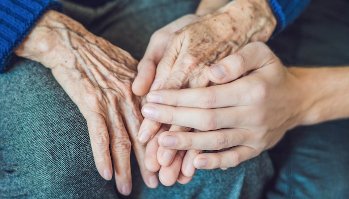 Người lớn tuổi nắm tay người trẻ tuổi